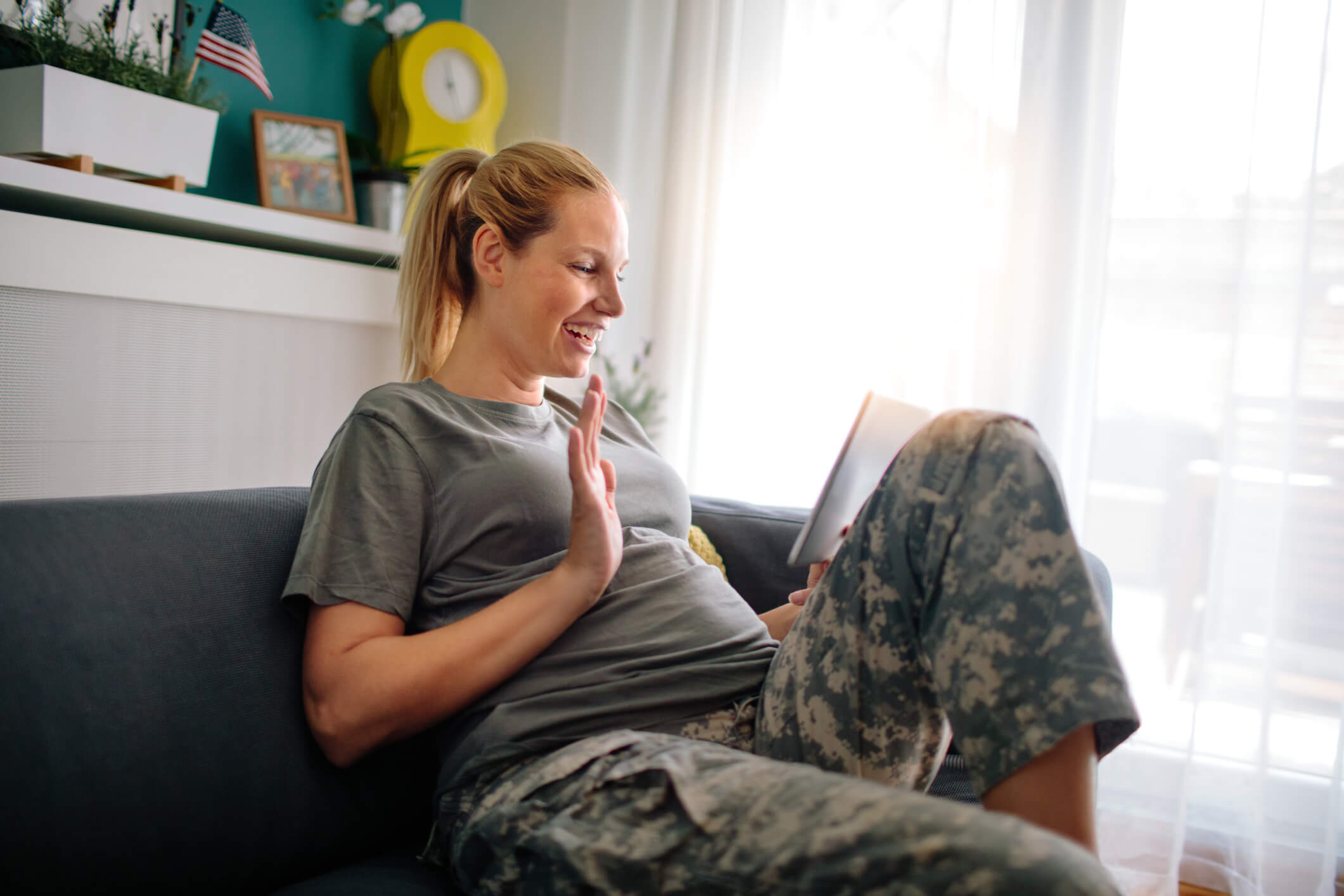 Beautiful pregnant female soldier using digital tablet at home.