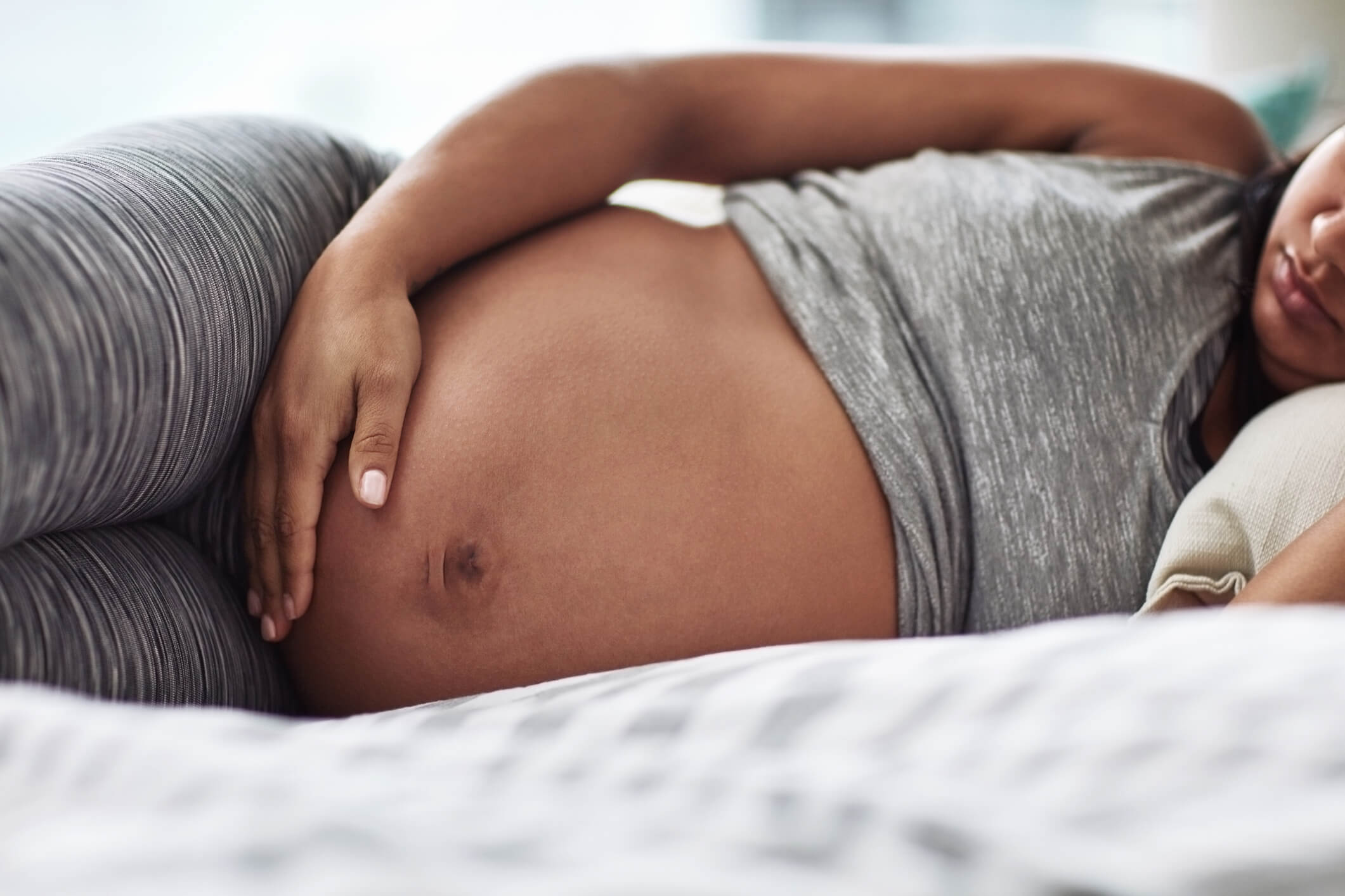 Cropped shot of an unrecognizable woman touching her pregnant belly while lying on bed