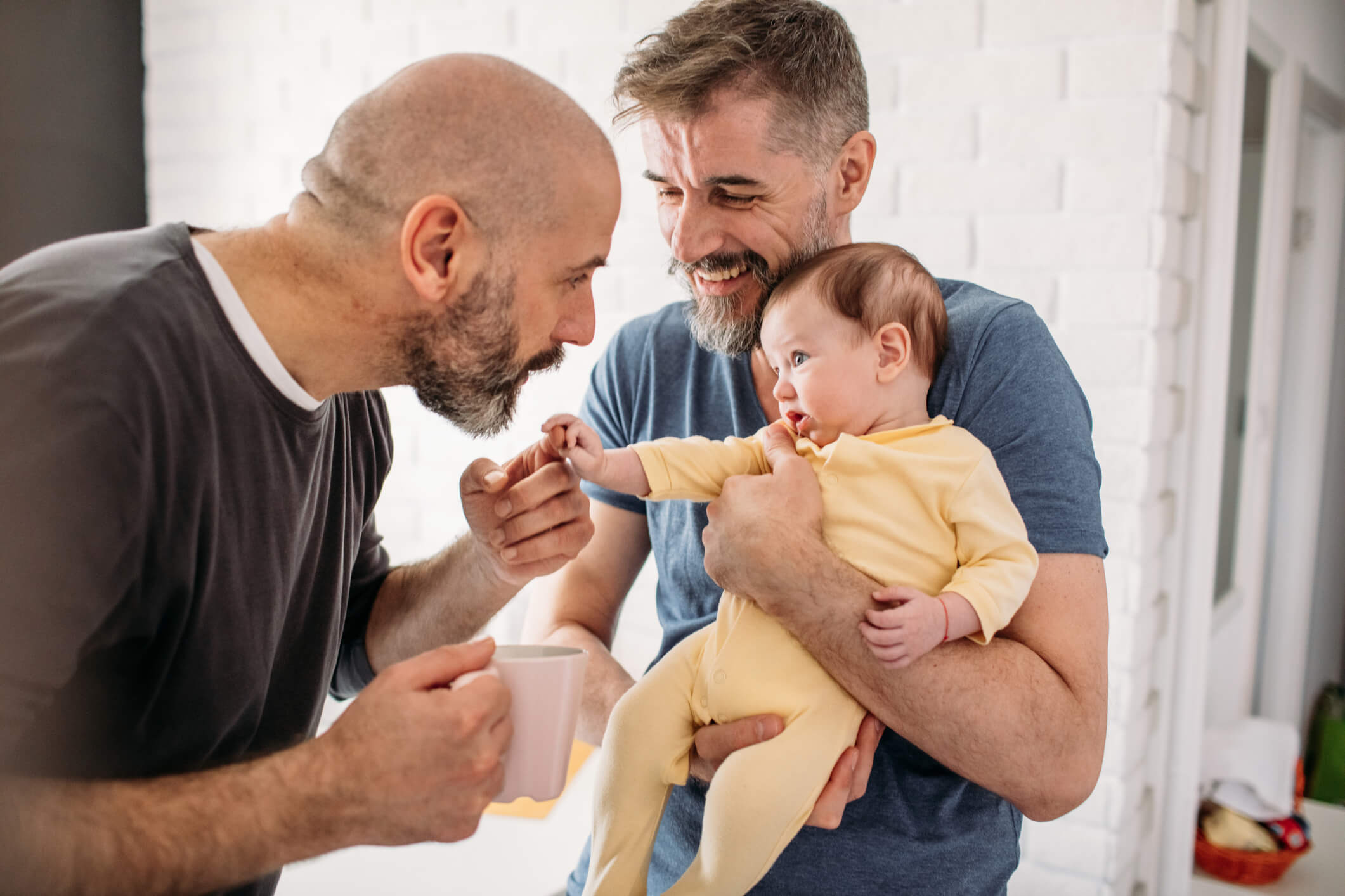 Gay dads with their adopted baby at home.