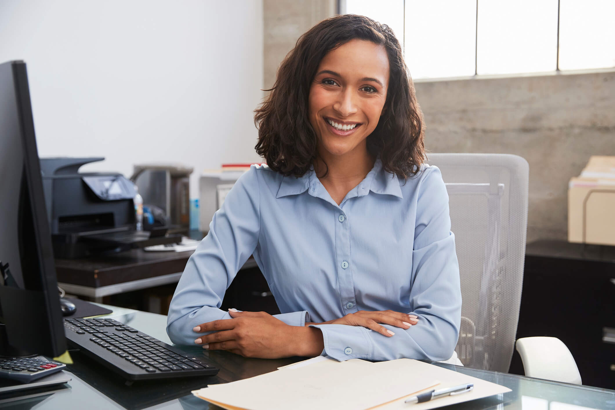 Young female professional at desk smiling to camera